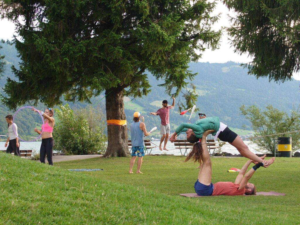 The Move Interlaken group is jaming. They do AcroYoga, play with a hoop and juggle with clups at Kifferinseli.
